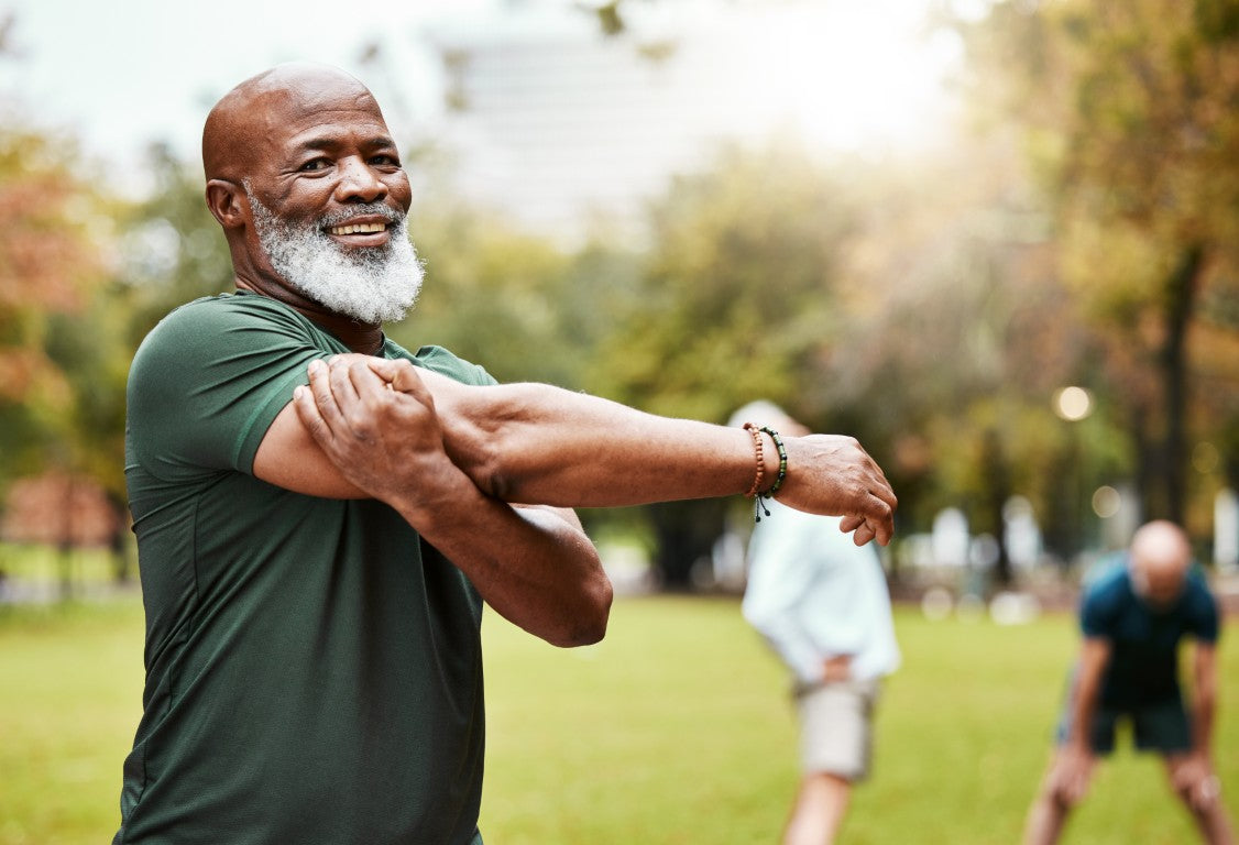 Man stretching in a park with trees and grass in the background